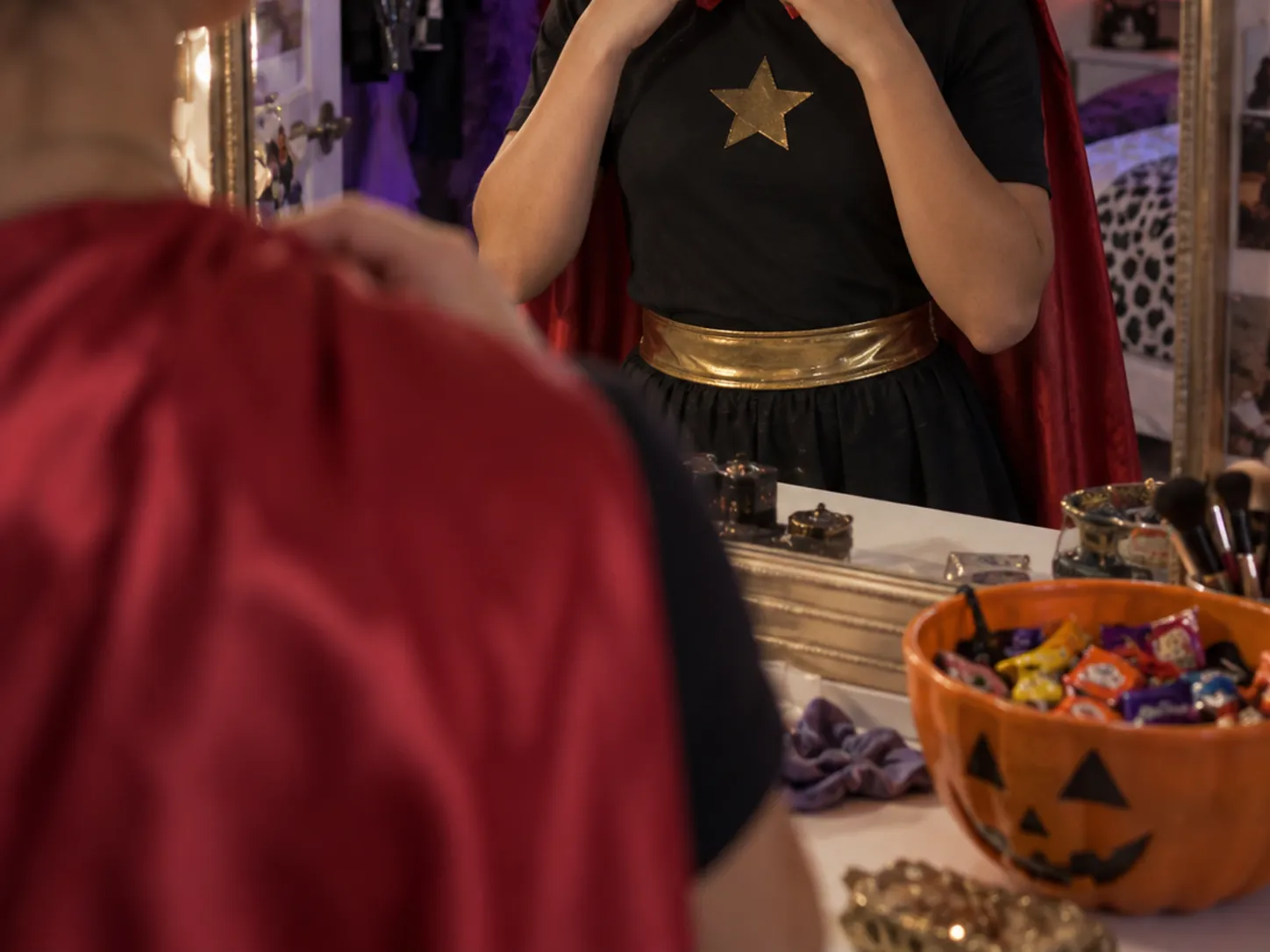 Teen adjusting a DIY Halloween costume in a mirror with purple room lights