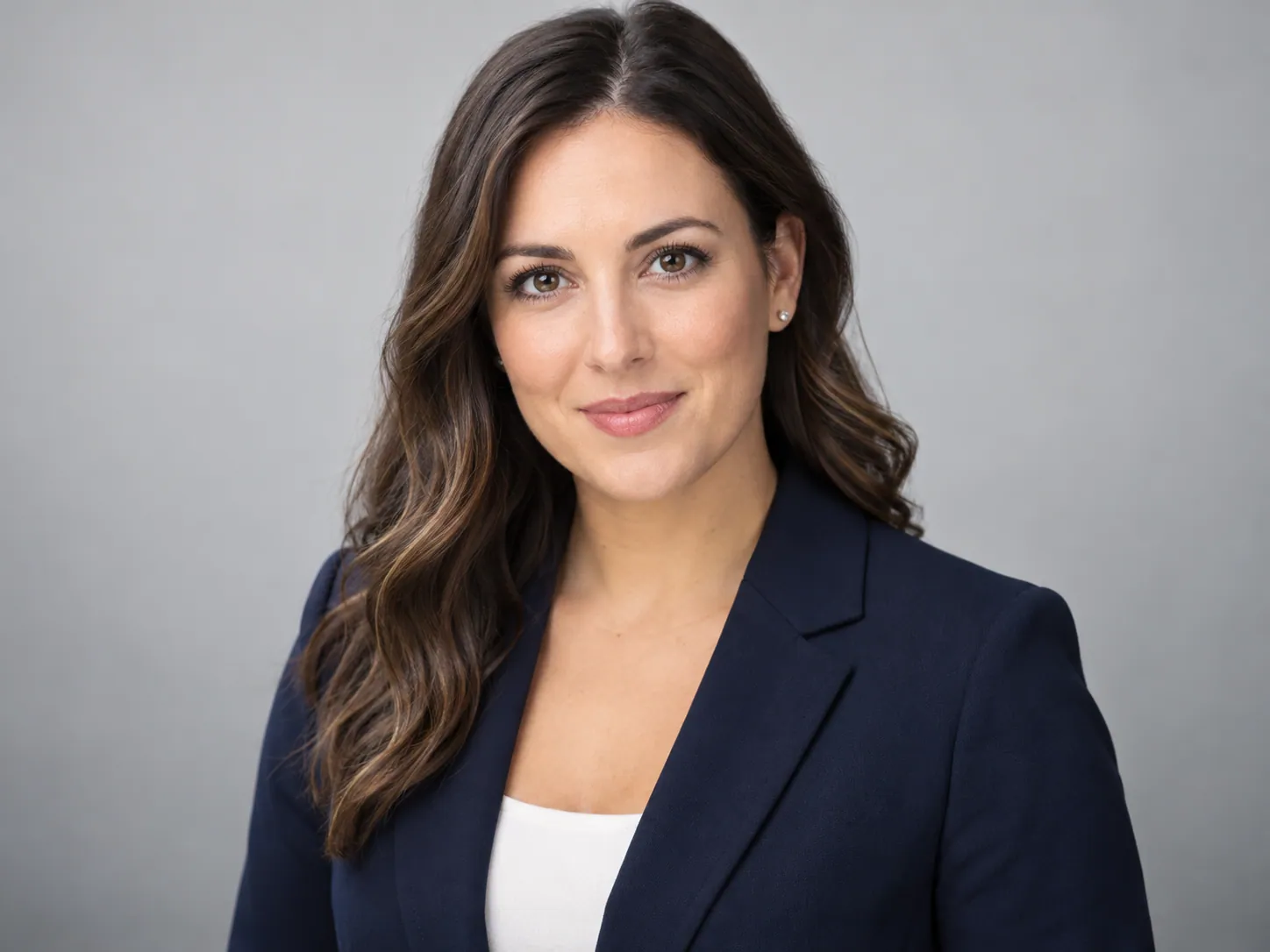 Classic professional headshot in a navy blazer on a grey backdrop