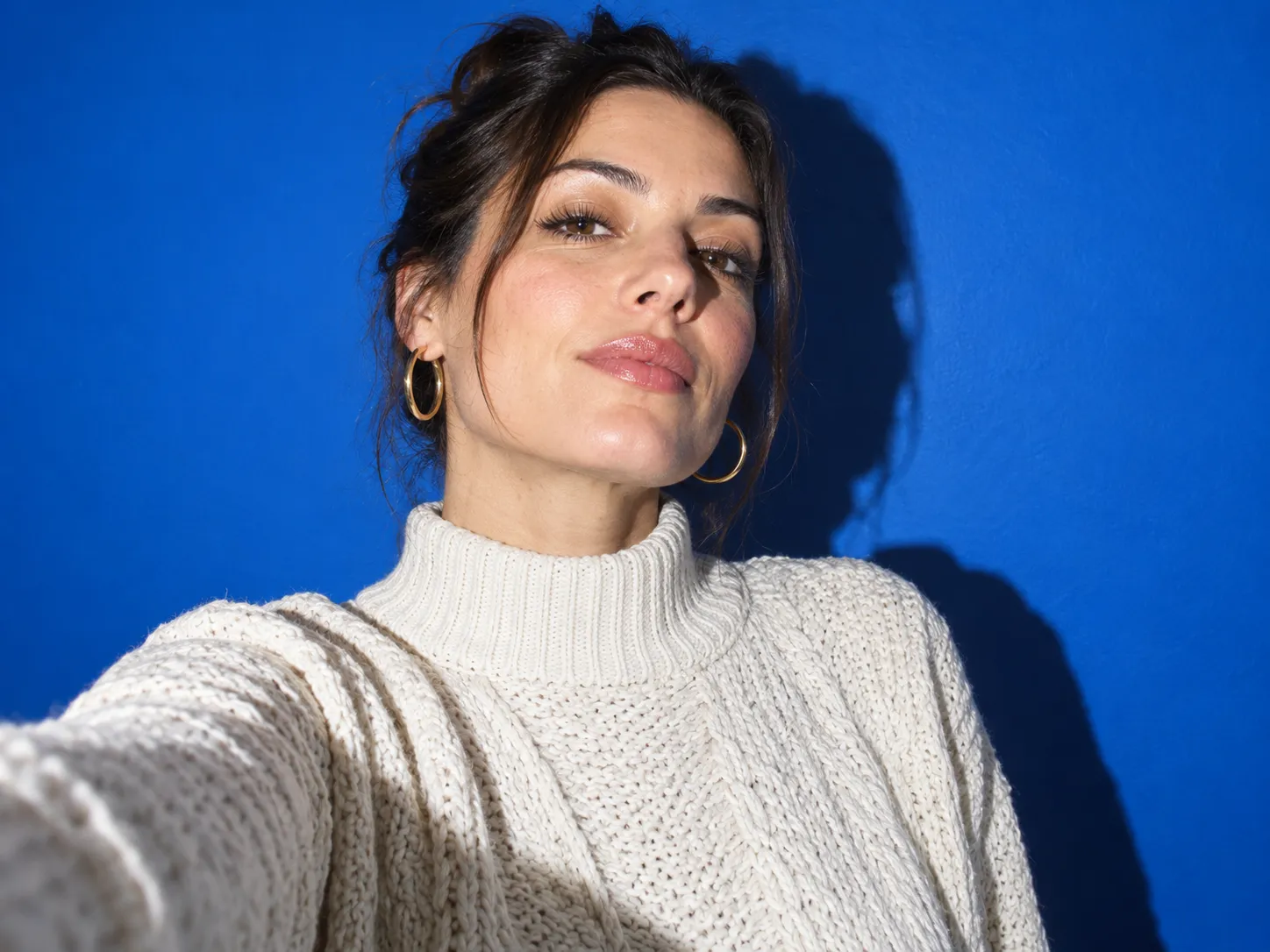 Fashion editorial selfie against a bold colored studio wall